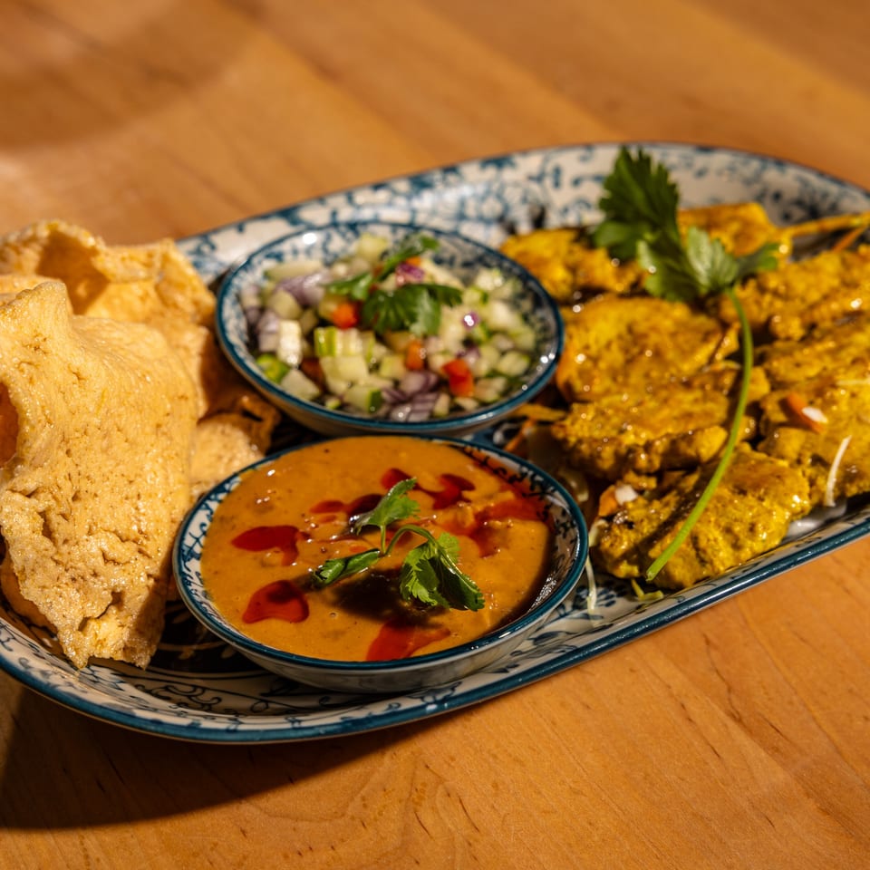 Relish Thai Cuisine's chicken satay skewers with peanut sauce, cucumber salad, and crispy crackers.